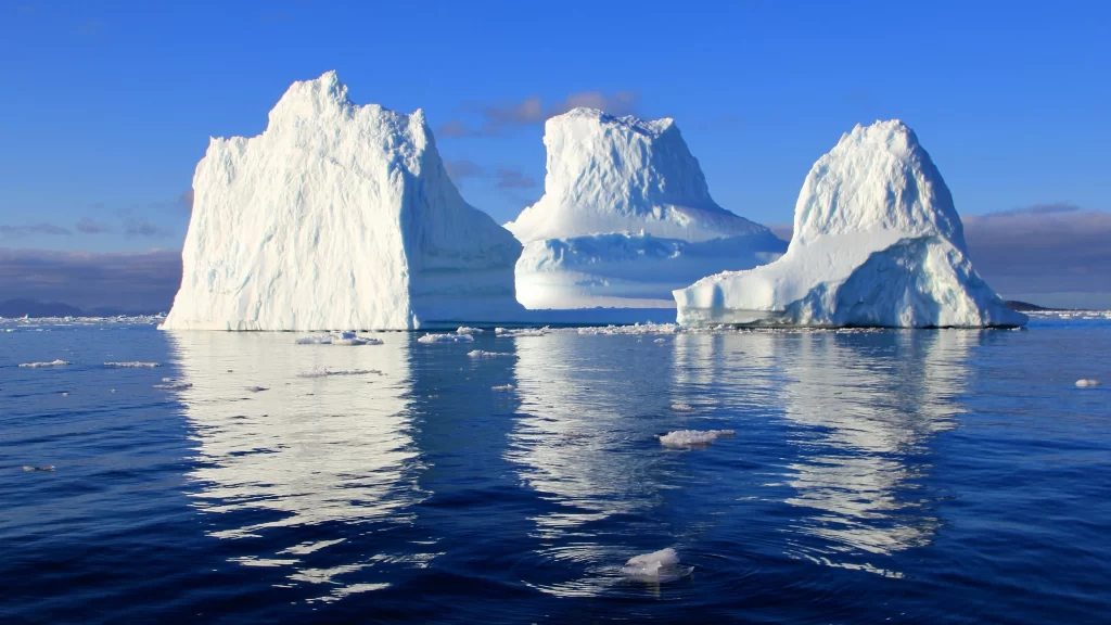 icebergs ocean reflection blue sky clouds sunlight cold