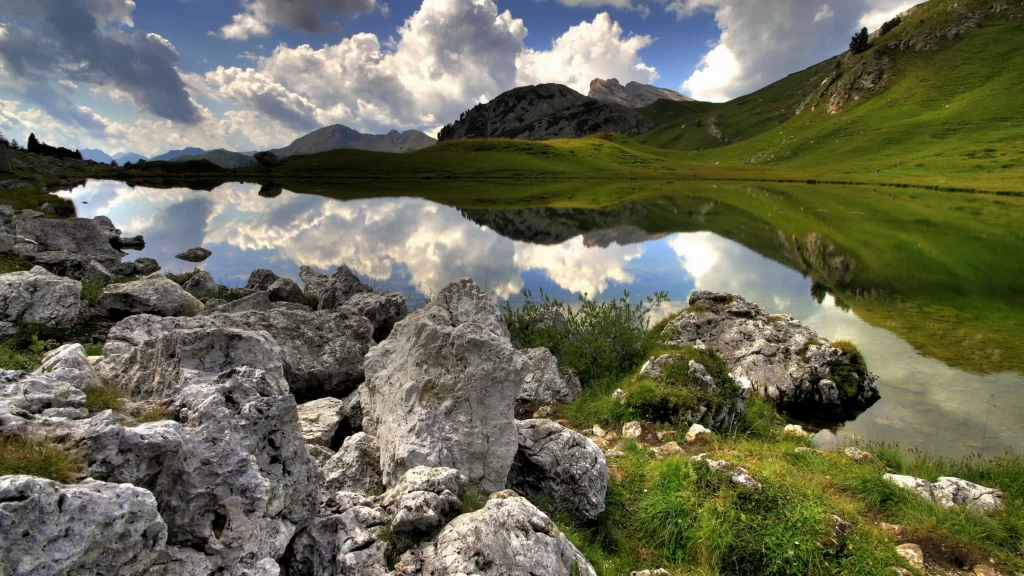 lake mountains clouds reflection rocks grass