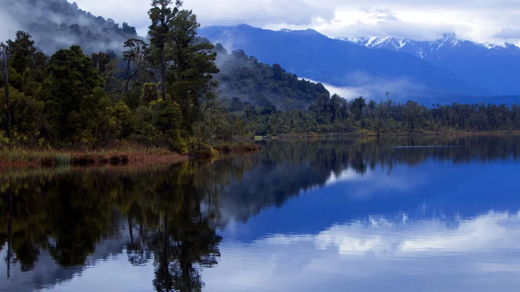 lake mountains trees reflection clouds mist