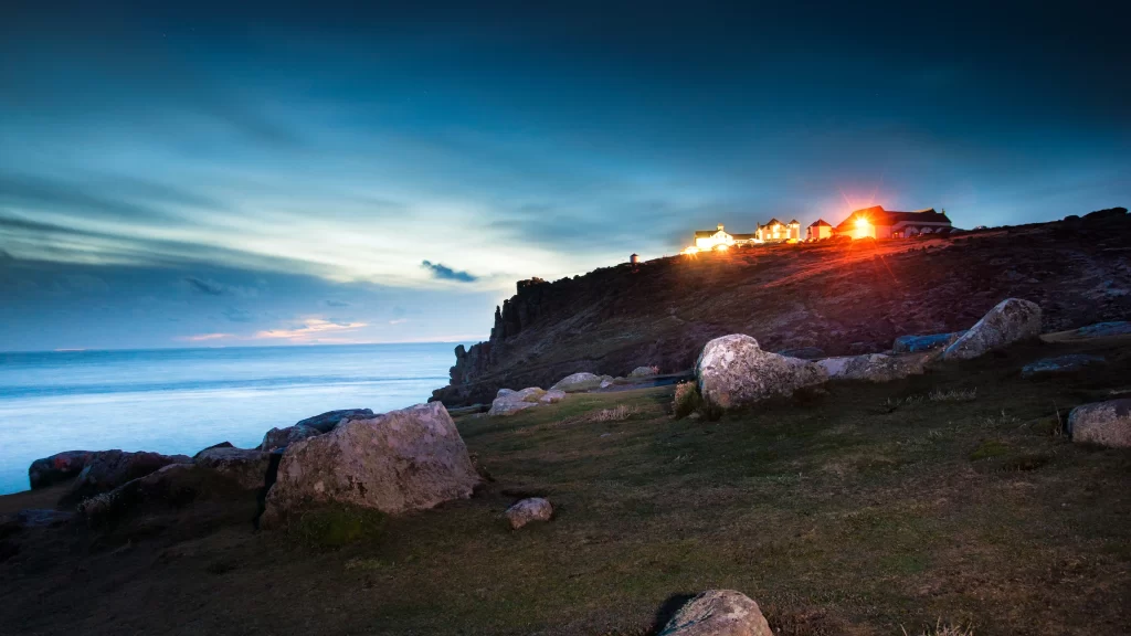 landscape twilight ocean rocks grass buildings