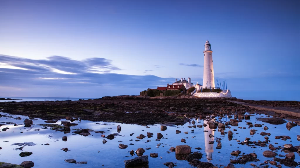 lighthouse reflection rocks water sky clouds