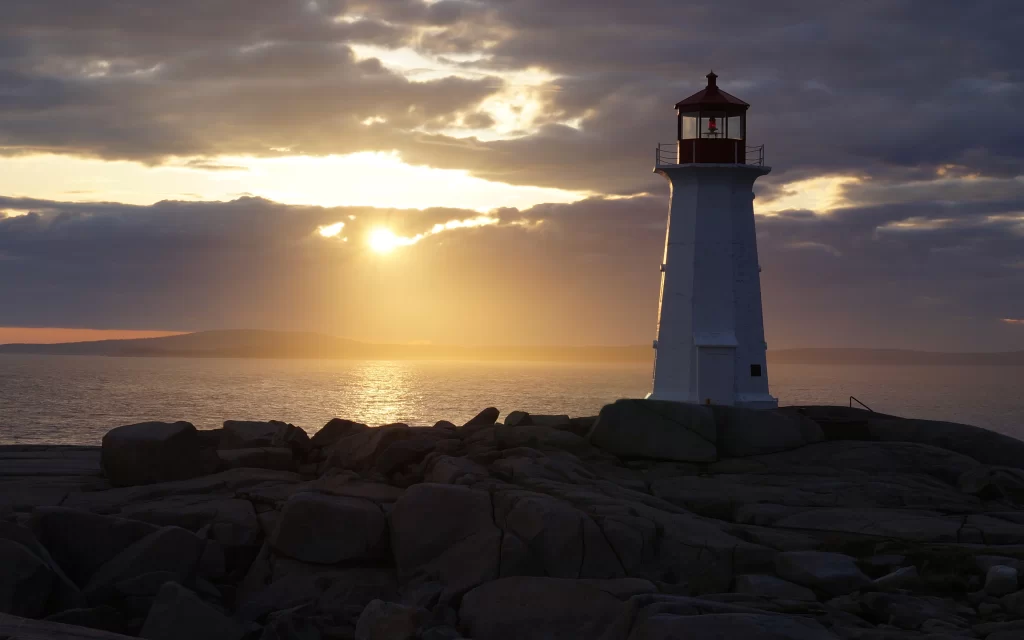 lighthouse sunset ocean rocks clouds