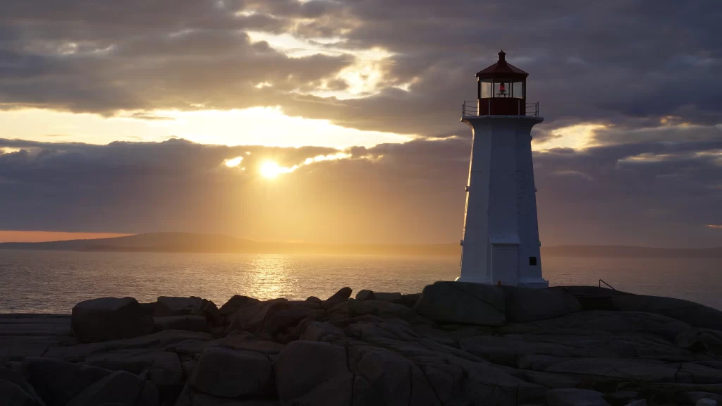 lighthouse sunset ocean rocks clouds