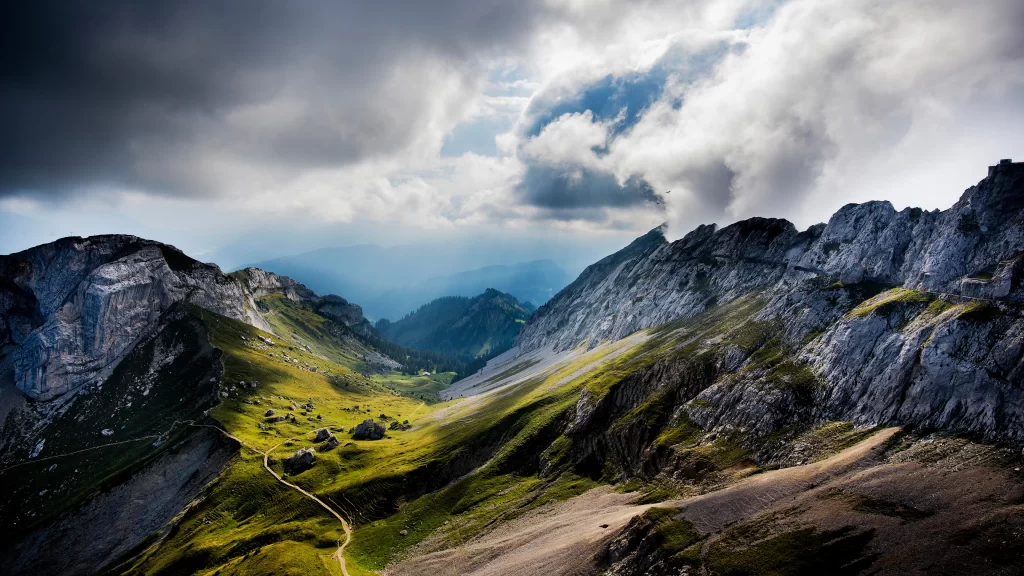 mountains clouds sunlight valley green path rugged landscape