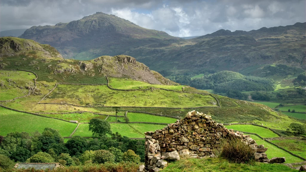 mountains green fields stone wall clouds sky
