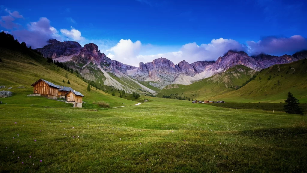 mountains green grass sky clouds cabin