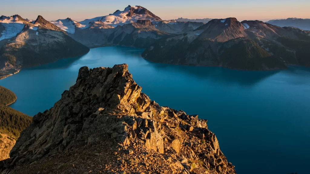 mountains lake rocky terrain snow peaks clear sky