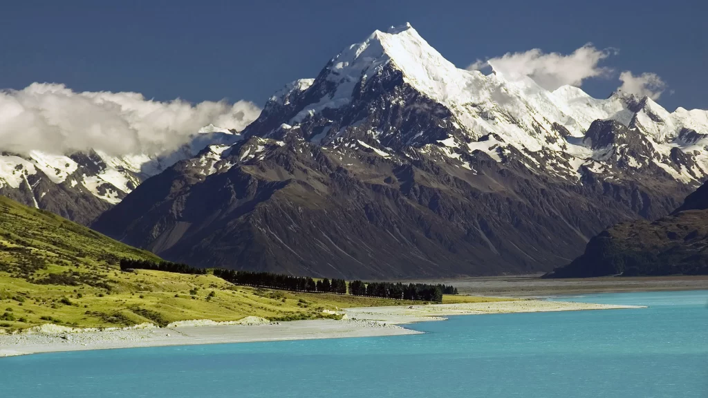 mountains snow lake green grass blue sky