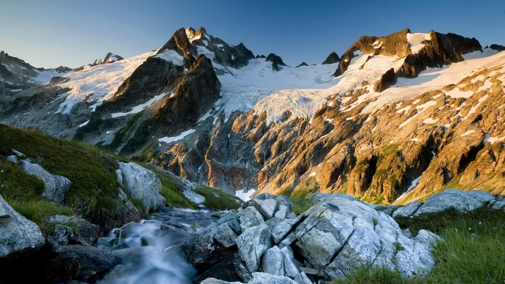mountains snow stream rocks grass