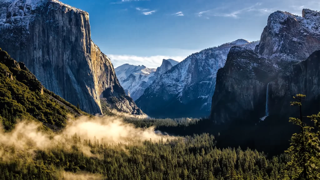 mountains valley mist trees snow sunlight