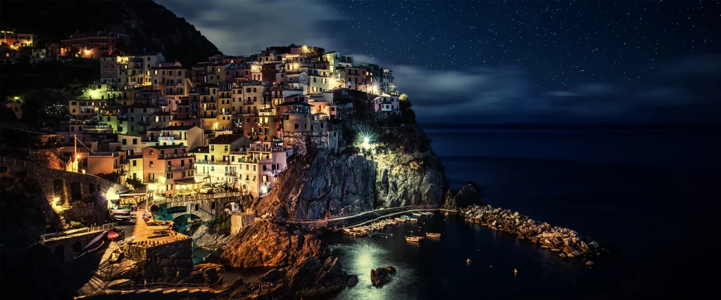 nighttime coastal town lights stars sea