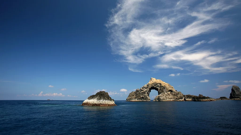 ocean rock arch sky clouds blue
