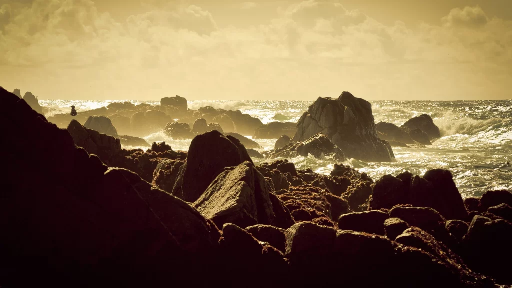 ocean rocks waves sunlight clouds