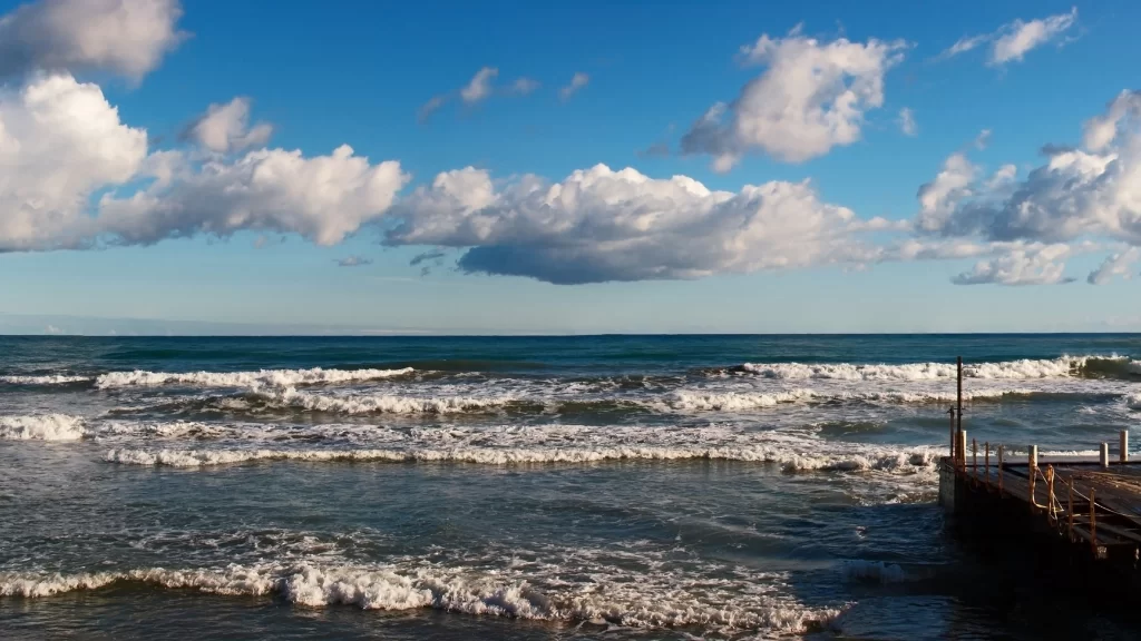 ocean waves blue sky white clouds wooden pier