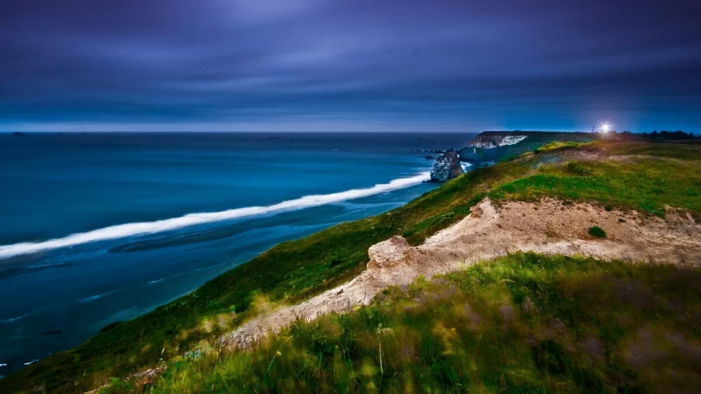 ocean waves cliffs lighthouse night sky