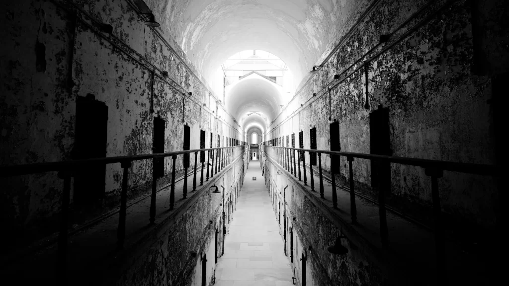 prison corridor black and white arched ceiling barred windows peeling paint hist