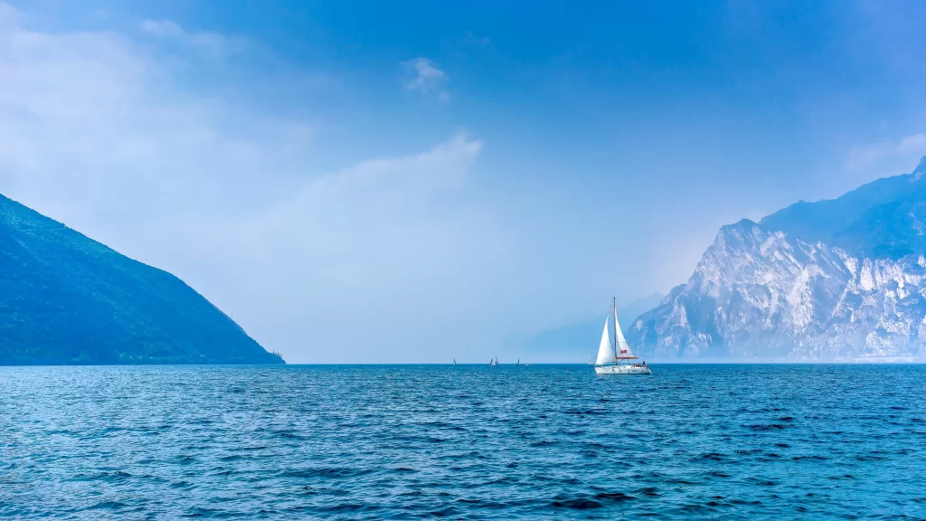 sailboat sea mountains sky clouds water horizon nature