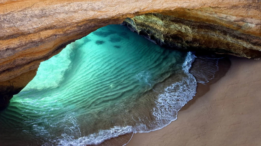 seaside cave turquoise water sandy beach ocean waves