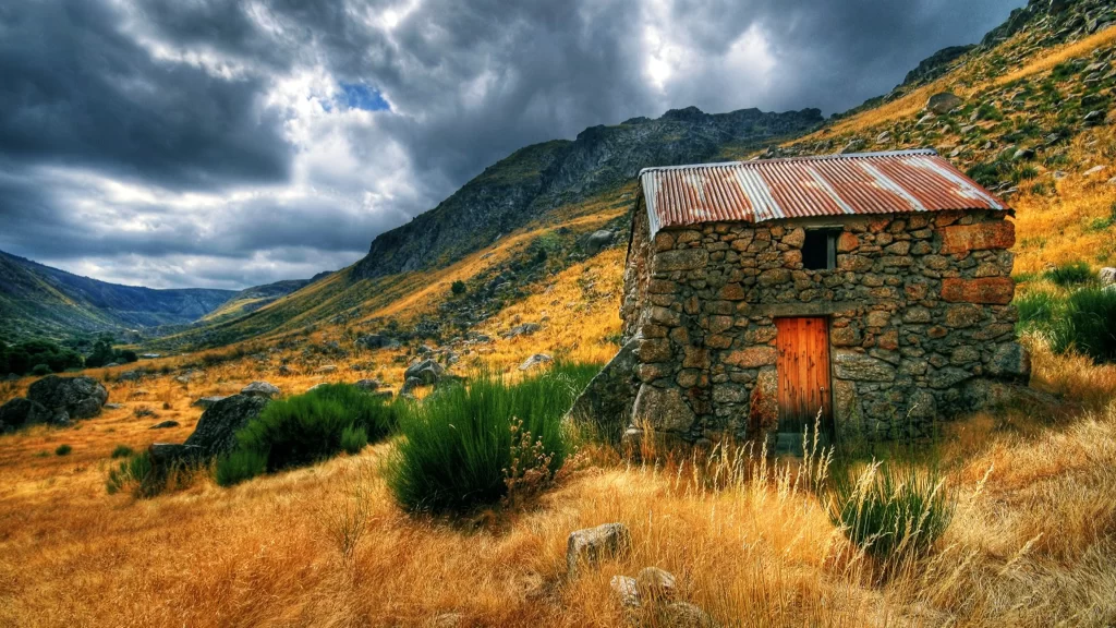 stone house rustic mountain cloudy sky golden grass wild plants