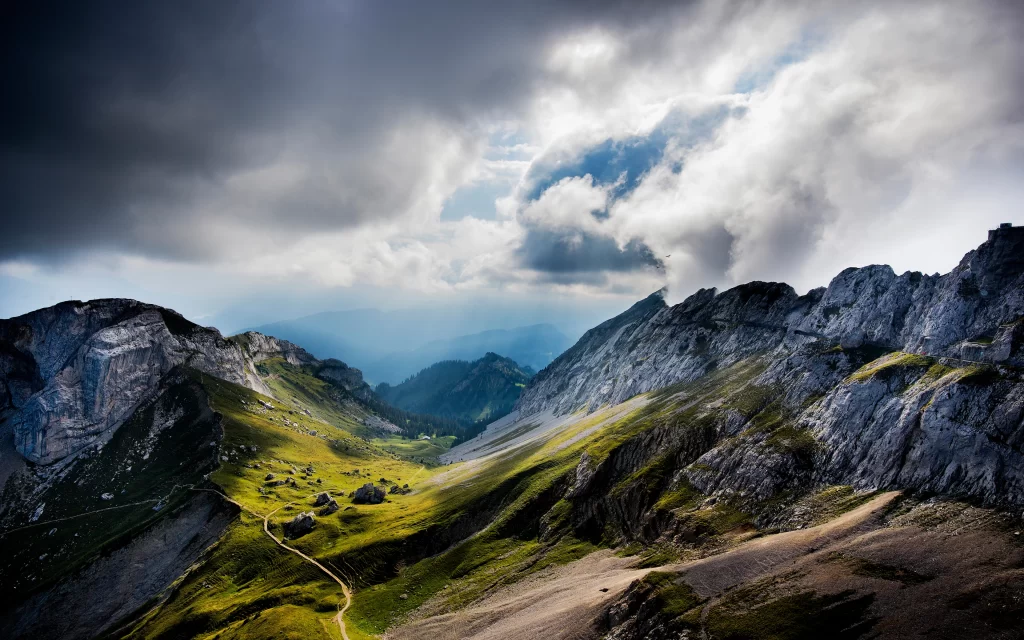 Mountainous Terrain Majestic Peaks Cloudy Sky Sunlight Rays Scenic Landscape