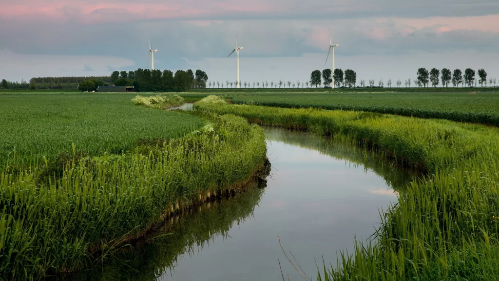 wind turbines river greenery sky clouds landscape