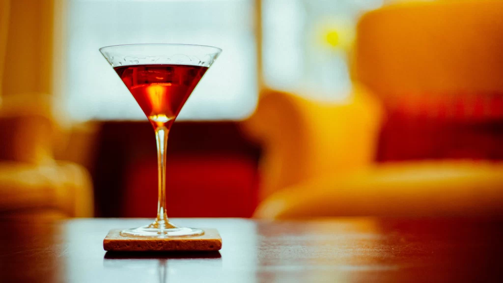 wine glass, red wine, cozy setting, wooden table, blurred background