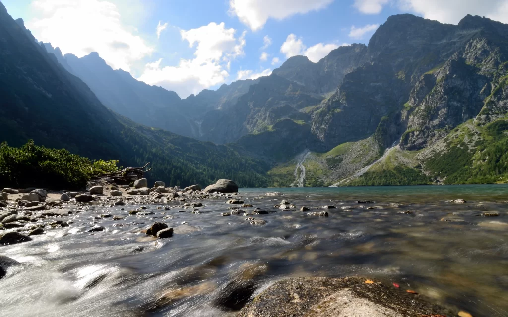 Mountainous Landscape Clear Water Rocky Shoreline Greenery Blue Sky