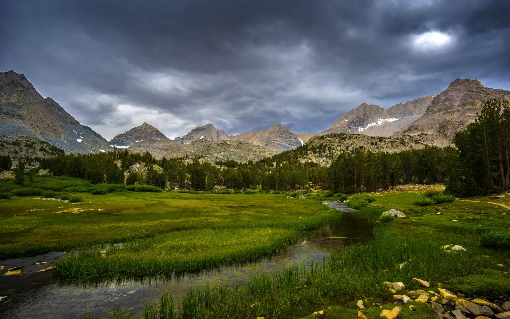 Mountainous Landscape Cloudy Sky Green Meadow Stream Forest Rocky Peaks