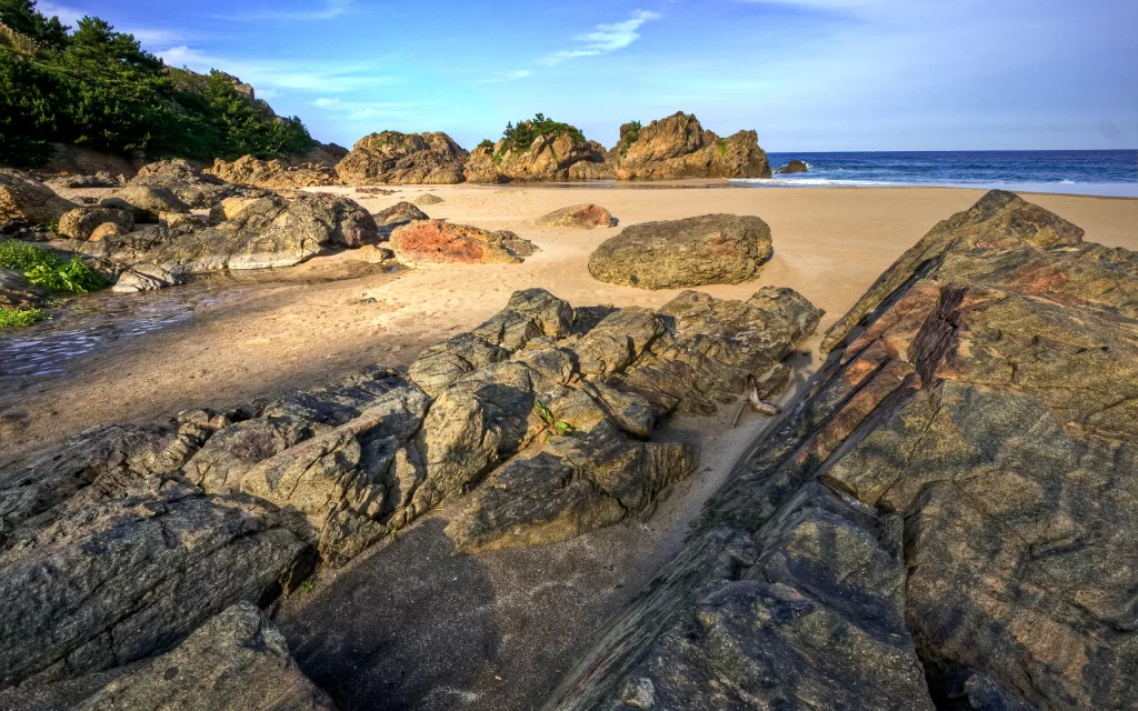 Rocky Beach Sandy Shoreline Ocean Waves Clear Sky Sunlight