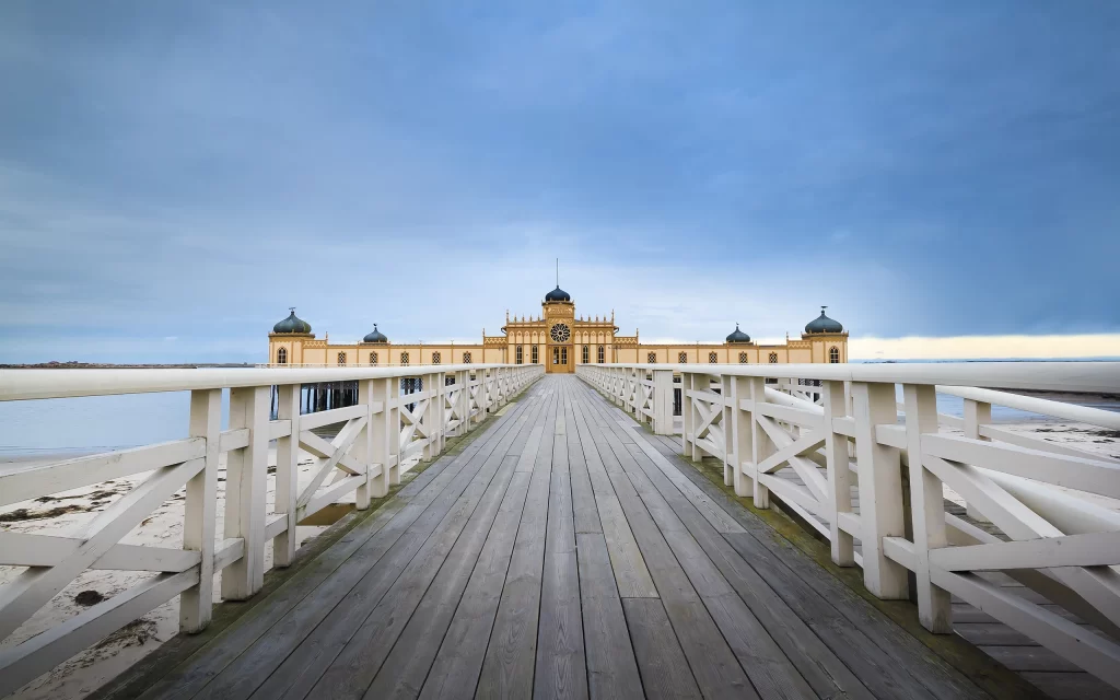 Wooden Pier Blue Sky Yellow Building White Railings Ocean View Symmetrical Architecture